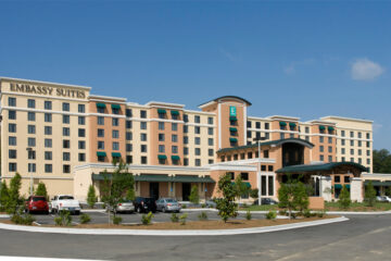 Kellan Cruz, CEO of Neyius Hotel Group, standing in front of an Embassy Suites hotel