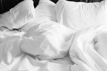Clean white hotel sheets and pillows freshly slept in at a Neyius Hotel Group managed property, highlighting sanitized bedding and comfortable guest rooms.