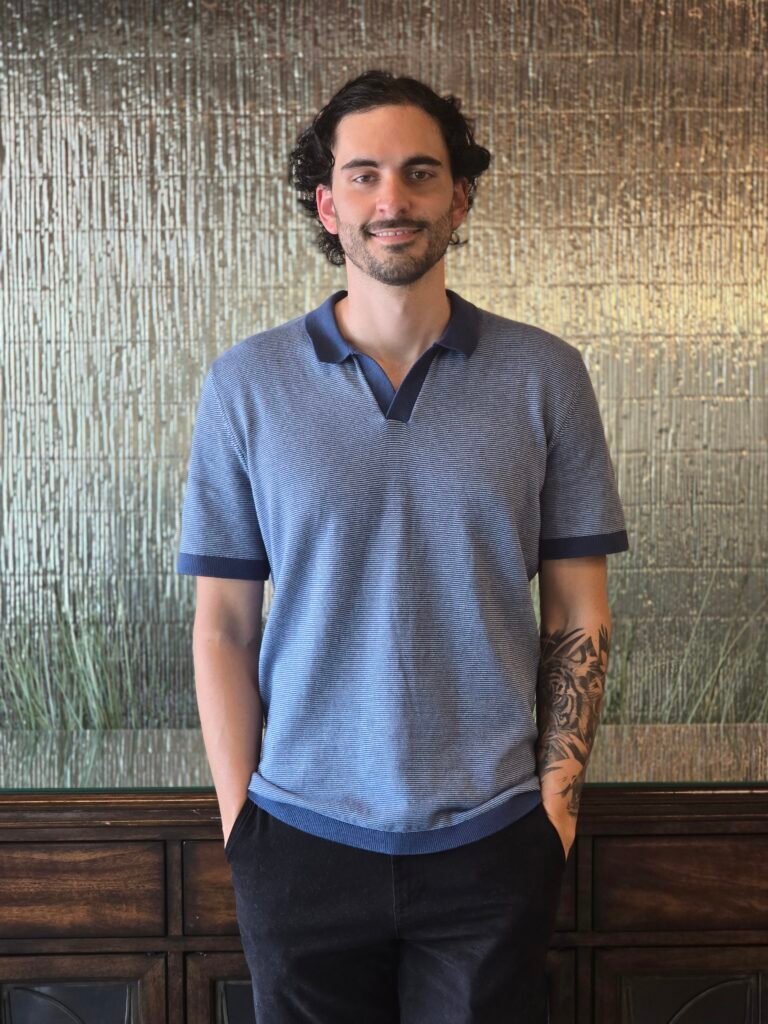 Nick Gallardo of Neyius Hotel Group standing indoors in a navy polo shirt
